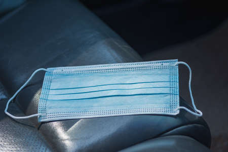 Disposable face mask on car seat with nature background.