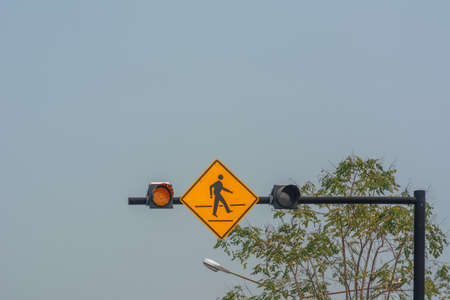 Over head warning sign for people crossing the road with blue sky background.の写真素材