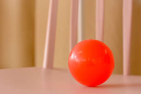 Red ball and pink chair on natural light background. Studio shot.