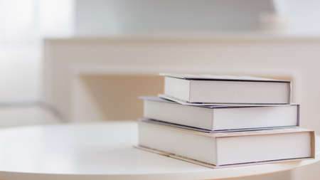 Books stacked on table in warm white room. Nature background.の写真素材