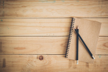 brown notebook and pencil on wood office table. Top view