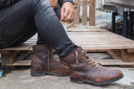 Young fashion man wearing in a black shirt, black jeans and brown leather boots on floor. Old leather boots.の写真素材