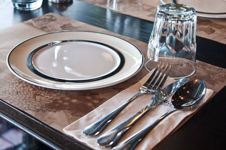  Plates with a silver fork, spoon, glass and a knife  on brown paper background の写真素材