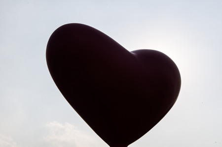 Silhouette of heart shape against blue skyの写真素材