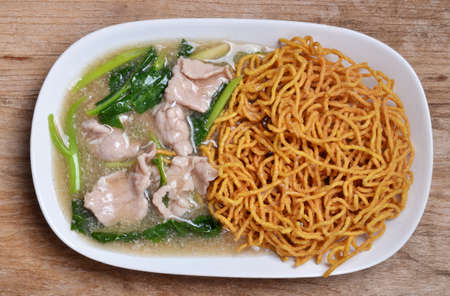 Noodle with pork and kale topping served in white bowlの写真素材