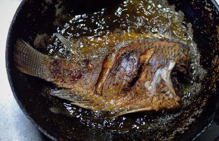 Fish frying in a pan in the outdoorsの写真素材