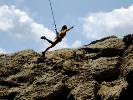 Girl jumping with a rope near the rockの写真素材