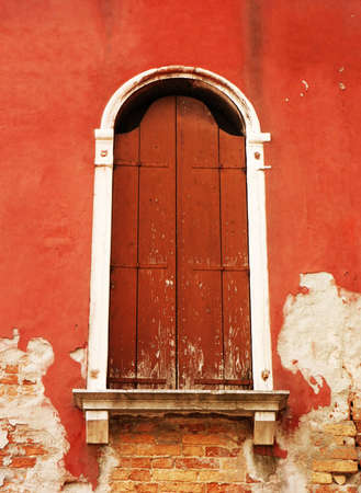 Old window with wooden shutters on the red wallの写真素材