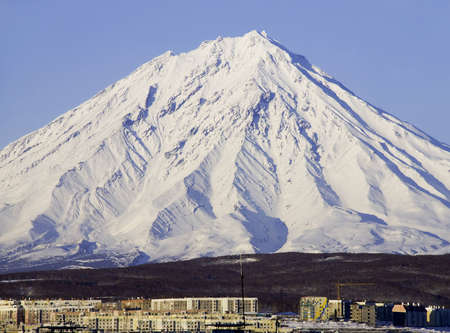 Dormant volcano covered with a snow and small northern town on Kamchatkaの写真素材