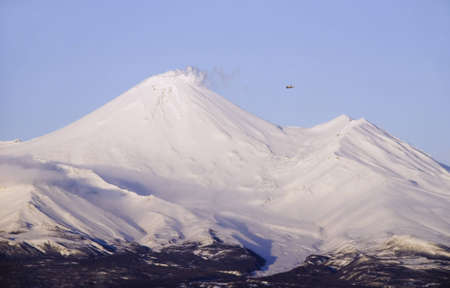 Active snowcapped volcano on Kamchatka and small aeroplaneの写真素材