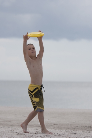 Young boy streatching to catch at beachの写真素材