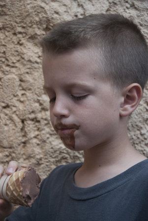 Messy boy loooking at ice cream coneの写真素材