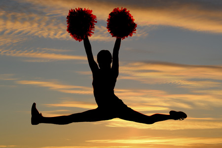 cheerleader silhouette leaping doing splits sunset backgroundの写真素材
