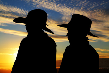 young cowboys silhouette wearing hats sunset 