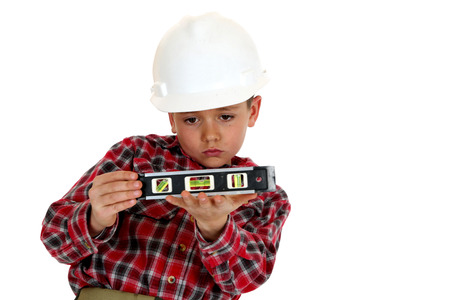 boy wearing hard hat holding a level