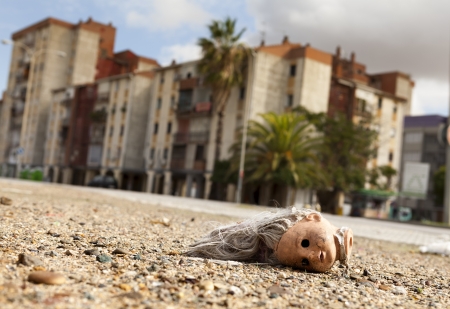 Broken doll head lying on the ground in a suburb on the outskirts of a mediterranean cityの写真素材
