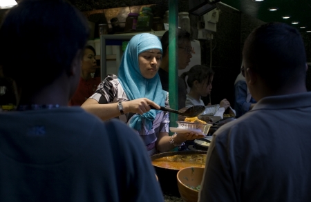 Camden Town, London, United Kingdom - April 29, 2007: A muslin young woman wearing a headscarf and serving typical oriental food at a food stall in Camden district. のeditorial素材