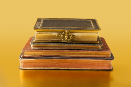 Some old books in horizontal position on a golden reflective surfaceの写真素材