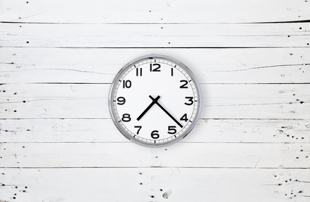 Very bright picture of a wall clock hanging in the center of a white plank
