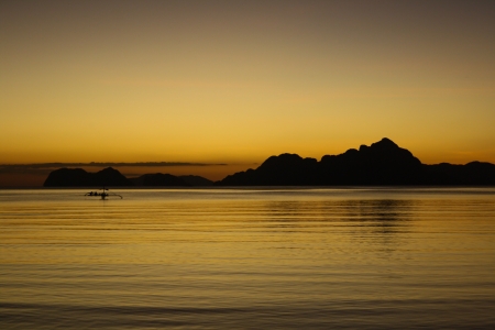 Sunset from El Nido beach with a silhoutte of a bangka boat. Palawan, Philippinesの写真素材