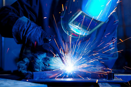 welder at work in a factory welding metal with sparks flying in the airの写真素材