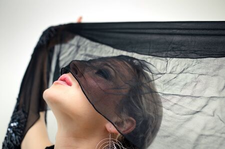 Beautiful young woman revealing her black veiled face.の写真素材