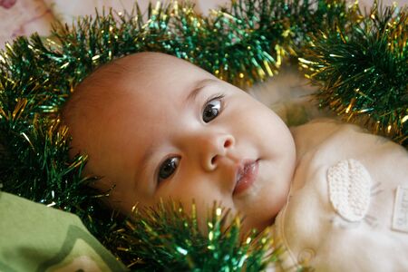 little baby lying in a bed with a Christmas garland