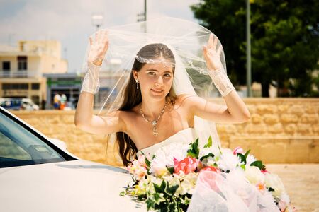bride with bouquet near the car on a hot summer dayの写真素材