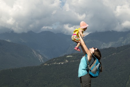 Mother throws up her baby in the sky in nature. hot summer day in the mountainsの写真素材