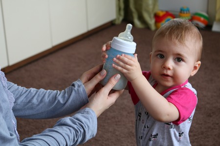 Mom gives a bottle of milk to their young child. horizontalの写真素材