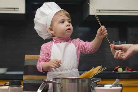 little cute child helps her mother cook pastaの写真素材