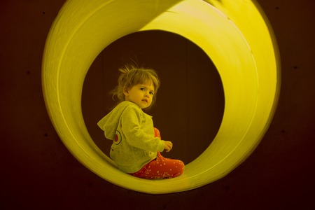 Little blond girl play and hide in toy tubeの写真素材