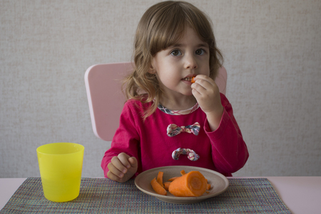 Cute little girl eats carrotの写真素材