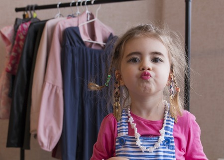 Clouse-up portrait emotional little girl background of a clothes rack