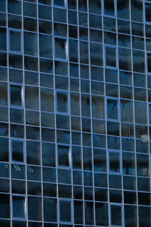 Front view of sky and cloud reflection on modern office building glass wall and windows in the city business areaの写真素材