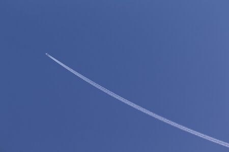 The white airplane fly in the sky, jet engine make the white line of smoke in the blue sky, for design about direction symbol.の写真素材