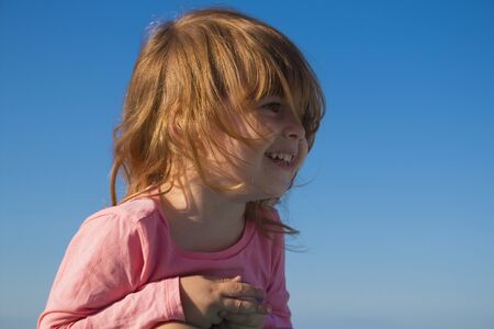 Close-up portrait of a cute, smiling young child on blue sky backgroundの写真素材