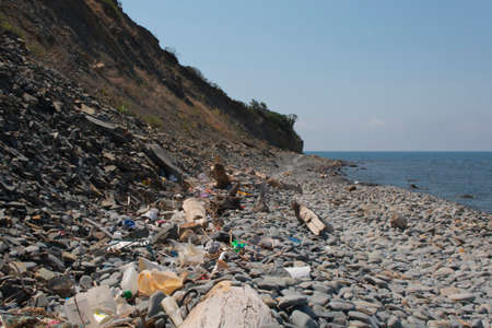 Spilled garbage on the beach. Empty used dirty plastic bottles. Dirty sea sandy shore the Black Sea. Environmental pollution. Ecological problem.の写真素材