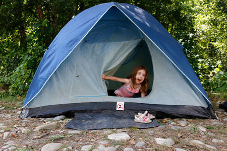 Portrait of emotional Little girl sits inside a tent and looking at camera. Grimacing child.の写真素材