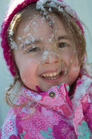 Emotional close up portrait of adorable female child in warm winter clothing, enjoys fresh air and beautiful sunny frosty day, happy to be outdoorの写真素材
