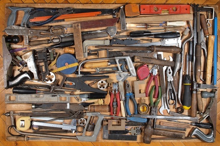 Various metalwork and carpentry tools, arranged on a wooden table.