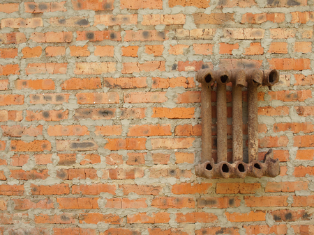 Ruined cast iron radiator for home on a brick wall.