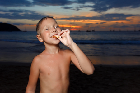 tanned boy after swimming eating a sandwich with ham and cheeseの写真素材