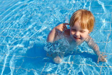 Happy little fair child boy in water in swimming poolの写真素材