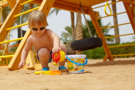 Small fair hair child boy in the playground in hot countryの写真素材