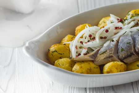 Herring with fried potatoes and onion on a plateの写真素材