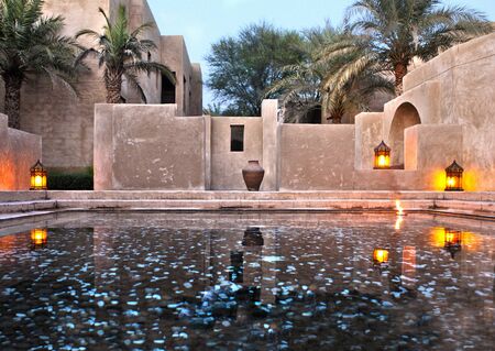 Low angle view on a reflection pool overlooking classical and traditional architectural style of Arabia illuminated with lanterns almost at dusk timeのeditorial素材