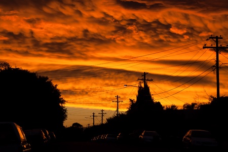 Dramatic sunset looking like a river of fire over an urban street with cars and streetlightsの写真素材