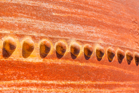 Dramatic orange, yellow and red rust markings and rivets on an old water tankの写真素材