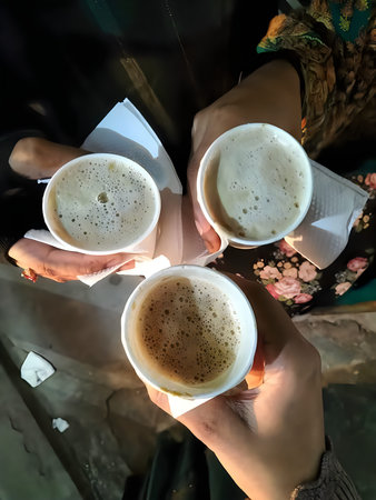 Three people toasting with cups of frothy coffee in a cozy outdoor settingの写真素材
